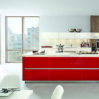 Kochinsel als roter Farbklecks in einem zurückhaltend, weißem Küchen-Ambiente.