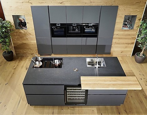 ÜBERRAGEND AUSGESTATTET: Performance-Muldenlüfter mit Top-Filtersystem, Pyrolyse-Backofen mit Profi-Bräter, Kombidampfgarer (beide mit Kerntempsensor), Kaffeeautomat, Wärmeschublade, großer Kühlschrank mit 0°-Zone, Gefrierschrank, 2-Zonen-Weinkühler! - ELEGANTE LUXUS-INSELKÜCHE. Wunderschöne matte Glasfronten in sanftem Lavaschwarz, geflammter afrikanischer Naturstein, Theke & Einsätze in echter Eiche, Volledelstahl-Armatur, Auszüge ringsum...