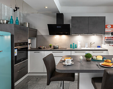 moderne L-Küche mit Arbeitsinsel und Sitzplatz - Koje 6 Lux Lack alpinweiß hochglanz/Riva beton grau