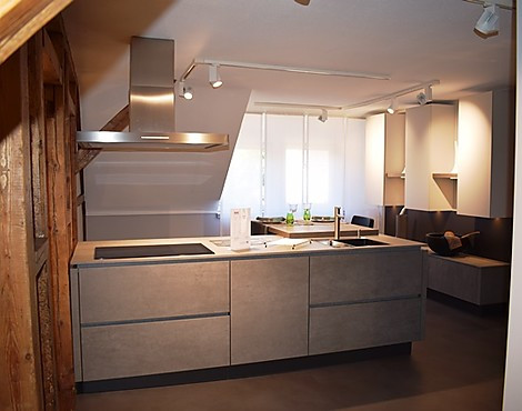 Harmonische Einbauküche mit einem grifflosen Design, Keramikarbeitsplatte. Sitzgelegenheit bzw. Essgelegenheit, sowie eine kleine Wohnwand und separaten Gerätehochschränke mit Keramikfronten. - ALNO Star Cera, Concretto Keramik