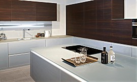 Designküche mit edel anmutender Glas-Arbeitsplatte in einem hellen und zeitlosen Grauton. Zuordnung: Stil Design-Küchen, Planungsart Detail Küchenplanung
