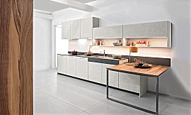 Exklusive Küchenzeile mit Front in Beton-Optik und praktischem Ansetztisch mit Oberfläche in edlem Walnuss-Furnier. Zuordnung: Stil Design-Küchen, Planungsart Küchenzeile