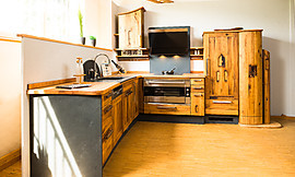 Altes Holz wurde hier zu neuen Küchenmöbeln verarbeitet. Die ungebändigte, rustikale Maserung des Eichenholzes macht die Altholzküche zum Unikat. Schwarzer Schiefer setzt einen attraktiven Kontrast. Zuordnung: Stil Landhausküchen, Planungsart Küchenzeile
