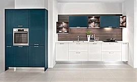 Einzeilige Küche mit matt lackierten Rahmenfronten in den Farben Weiß und Deep Blue. Besondere Leichtigkeit erhält die Küchenzeile durch die schwebende sockelfreie Konstruktion. Die Nischenrückwand in dunkler Holzoptik schafft einen gemütlichen Akzent und in den beleuchteten Regalen werden Geschirr und Accessoires optimal in Szene gesetzt. Zuordnung: Stil Design-Küchen, Planungsart Küchenzeile