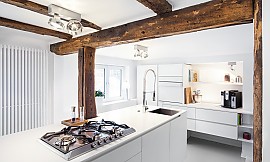 Koch- und Zubereitungsinsel der weißen Designerküche wurden um das Fachwerk herumgeplant. Zuordnung: Stil Moderne Küchen, Planungsart U-Form-Küche