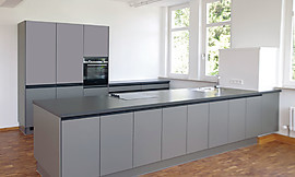 Die graue Inselküche besticht mit modernem Design und bietet ausreichend Stauraum und Bewegungsfreiheit beim Kochen. Zuordnung: Stil Moderne Küchen, Planungsart Küche mit Küchen-Insel