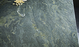 Die Küchenarbeitsplatte aus dem Naturstein Alpengrün zeichnet sich durch eine attraktive Farbgebung und eine einzigartige Maserung in den verschiedensten Grüntönen aus und wird bei dieser Kochinsel mit hellem Holz kombiniert. Zuordnung: Stil Luxusküchen, Planungsart Küche mit Sitzgelegenheit