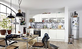 Diese schlichte Küchenzeile in klassischem Weiß passt optimal in kleinere Räume. Die Hängeschränke sind aufgeteilt in offene Regale und geschlossene Module. Das Design der Rückwand in grau-weißer Ziegeloptik ist ein echter Hingucker. Zuordnung: Stil Moderne Küchen, Planungsart Küche mit Sitzgelegenheit