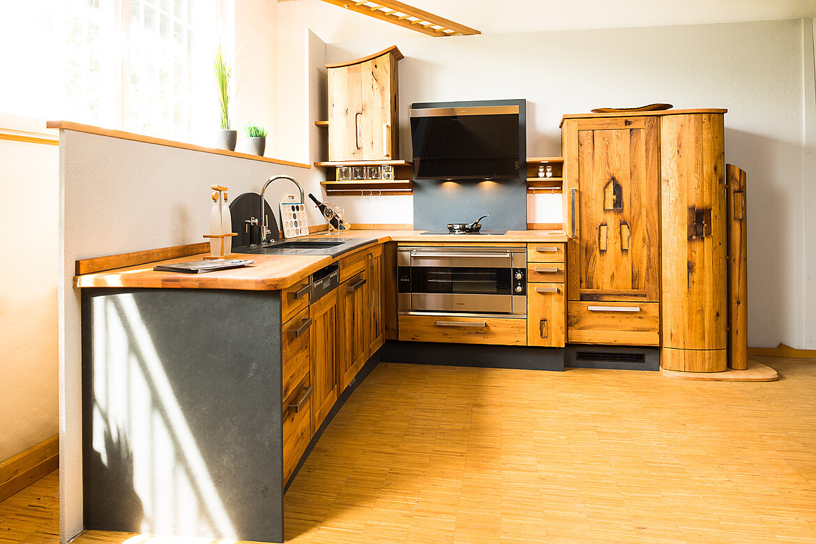 Altes Holz wurde hier zu neuen Küchenmöbeln verarbeitet. Die ungebändigte, rustikale Maserung des Eichenholzes macht die Altholzküche zum Unikat. Schwarzer Schiefer setzt einen attraktiven Kontrast. Zuordnung: Stil Landhausküchen, Planungsart L-Form-Küche