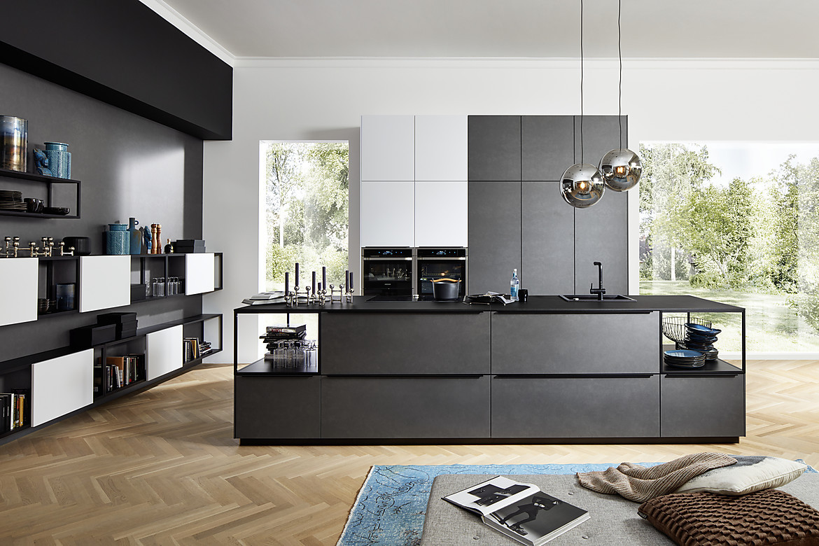 Das Küchenmodell Ferro Blaustahl begeistert mit schlichter Eleganz und hochwertigen Küchenfronten aus Echtmetall. Weiße Lackoberflächen setzen einen hellen Akzent in der sonst dunklen Küche. Zuordnung: Stil Luxusküchen, Planungsart Küche mit Küchen-Insel