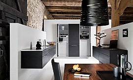 Elegantes Eichenfurnier Schwarz bestimmt die Raumatmosphäre und schafft in der weitläufigen Architektur eine verbindende Linie zwischen den sockelfreien Küchen-Wohnelementen. Zuordnung: Stil Klassische Küchen, Planungsart U-Form-Küche