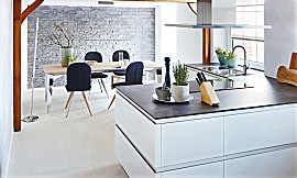 Ideal für Liebhaber des puristischen Küchendesigns: Rein weiße Küchenfronten in effektvoller Hochglanz-Ausführung gepaart mit geradlinigen Formen und grifflosem Design. Zuordnung: Stil Design-Küchen, Planungsart Küche mit Sitzgelegenheit