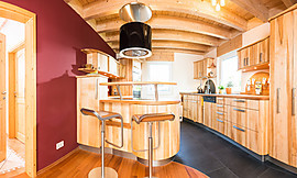 Diese Schreinerküche wurde maßgefertigt. Aus hellem Ahorn ist eine große Küche mit Theke entstanden. Runde und geschwungene Formen sorgen für einen modernen Holz-Look. Zuordnung: Stil Moderne Küchen, Planungsart Küche mit Küchen-Insel